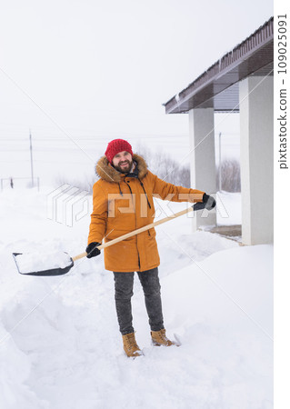 Man is clearing the snow near house and on staircases hovelling at the winter season. Winter storm and season specific 109025091