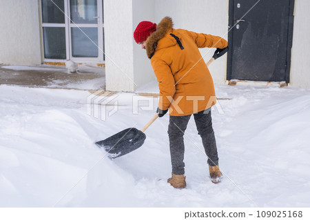 Man cleaning snow from sidewalk and using snow shovel. Winter season 109025168