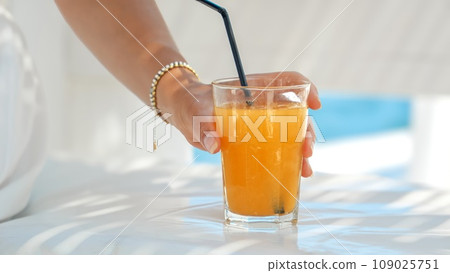 Delighted brunette woman enjoys her orange juice at sea beach cafe. Essence of summertime, holiday escape, relaxation, and wanderlust Delighted brunette woman enjoys her orange juice at sea beach cafe. Essence of summertime, holiday escape, relaxation, and wanderlust 109025751