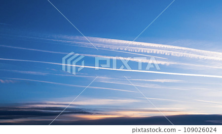 Cloudscape with trail of jet plane. Vapor trail from jets in a blue sky Cloudscape with trail of jet plane. Vapor trail from jets in a blue sky 109026024