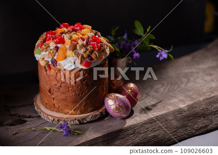 Easter Cake with dried fruits and nuts on a wooden table. Delicious traditional bakery and painted eggs for the main orthodox holiday. Easter Cake with dried fruits and nuts on a wooden table. Delicious traditional bakery and painted eggs for the main orthodox holiday. 109026603