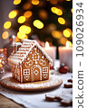 Gingerbread house on table. Defocused lights of Christmas garland. Evening in the living room. Holiday mood.  109026934