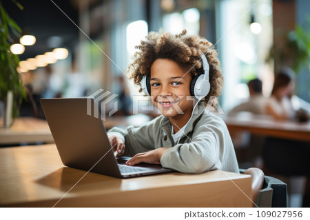 Kid with headphones uses laptop at home 109027956