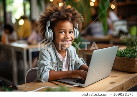 Kid with headphones uses laptop at home Kid with headphones uses laptop at home 109028175