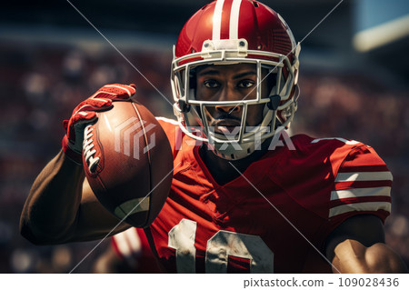 American football player of African descent in a red uniform runs with the ball 109028436