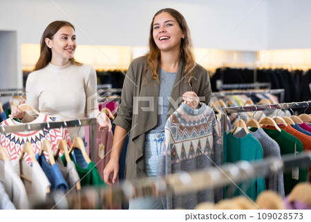 Positive young women friends choosing winter sweater in fashion store 109028573