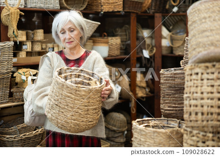 Elderly woman choosing basket in store Elderly woman choosing basket in store 109028622
