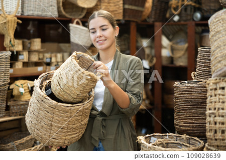 Girl looks at wicker basket in store. 109028639