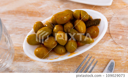 Light snack - bowl with pickled green olives and small cucumbers, gherkins 109029073