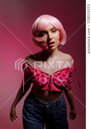 A female model stands on a pink background at a photo shoot in the studio. A female model stands on a pink background at a photo shoot in the studio. 109029353