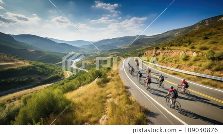 cyclists riding through a winding mountain road, with a beautiful scenic landscape 109030876