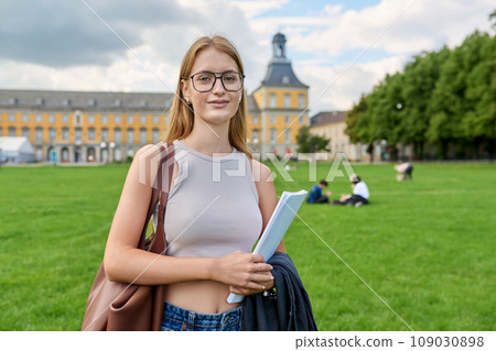 Young girl student posing outdoors, background of educational building Young girl student posing outdoors, background of educational building 109030898