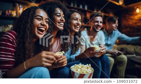 A group of friends gathered on a sectional sofa, watching a movie and eating popcorn 109031072