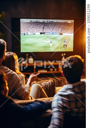 An extended family of grandparents, parents, and kids gathered around a large screen TV, 109031299