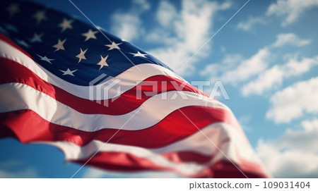 a flag waving in the wind with a blurred background of blue sky and clouds. 109031404