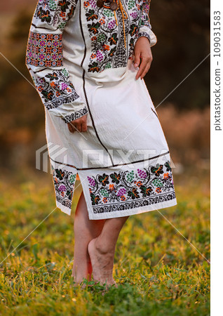 Embroidered and unique petticoat, a girl walks barefoot in the field in an embroidered shirt. Embroidered and unique petticoat, a girl walks barefoot in the field in an embroidered shirt. 109031583