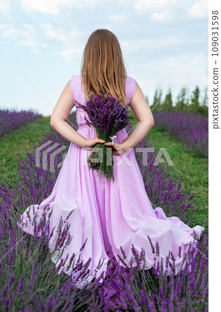 A bouquet of lavender and a girl in a purple dress, back view of the girl. 109031598