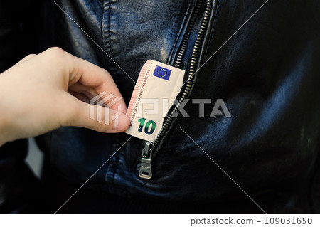 Hand pulls paper money and card out of pocket. A thief robbed a man. Cash theft, criminal concept. 109031650