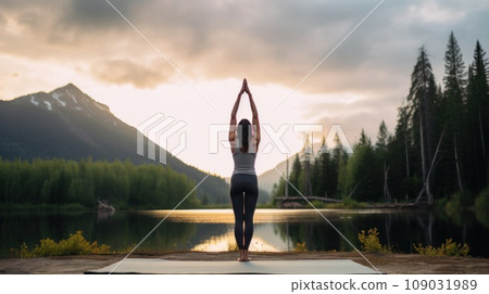 A woman doing a handstand on a yoga mat, with a peaceful, serene setting in the background 109031989