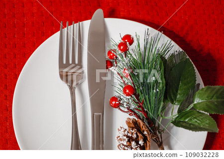 Christmas table setting. Plate and cutlery on red napkin. Decoration for a festive dinner. Christmas table setting. Plate and cutlery on red napkin. Decoration for a festive dinner. 109032228