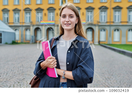 Young girl student posing outdoors, background of educational building Young girl student posing outdoors, background of educational building 109032419