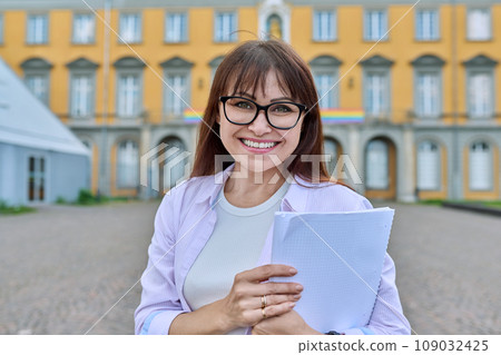 Middle-aged female teacher posing against background of educational building 109032425
