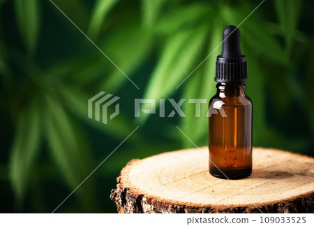 CBD hemp oil in a bottle against cannabis leaf background. Hemp herbal alternative medicine. 109033525