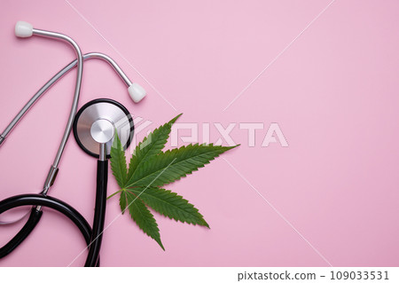 Medical cannabis leaf near and stethoscope top view on pink background. Hemp alternative medicine concept. Medical cannabis leaf near and stethoscope top view on pink background. Hemp alternative medicine concept. 109033531