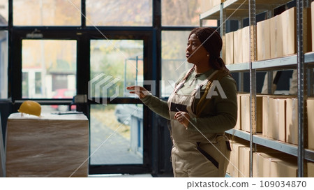 Employee in warehouse using AR holographic technology to visualize how to best stack merchandise on shelves to make room for more. Worker in storage establishment uses augmented reality Employee in warehouse using AR holographic technology to visualize how to best stack merchandise on shelves to make room for more. Worker in storage establishment uses augmented reality 109034870