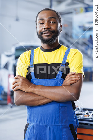 Portrait of proud BIPOC repairman in auto repair shop tasked with changing cars brake fluid. Qualified expert in garage ready to start doing checkups on vehicles in garage workspace Portrait of proud BIPOC repairman in auto repair shop tasked with changing cars brake fluid. Qualified expert in garage ready to start doing checkups on vehicles in garage workspace 109034911