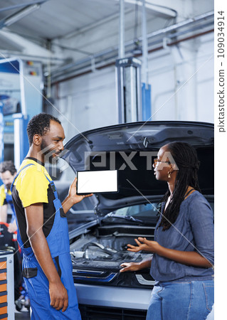 Licensed mechanic in car service uses mockup tablet to order new exhaust pipes for defective vehicle. Happy garage professional shows client needed components replacement on isolated screen device Licensed mechanic in car service uses mockup tablet to order new exhaust pipes for defective vehicle. Happy garage professional shows client needed components replacement on isolated screen device 109034914
