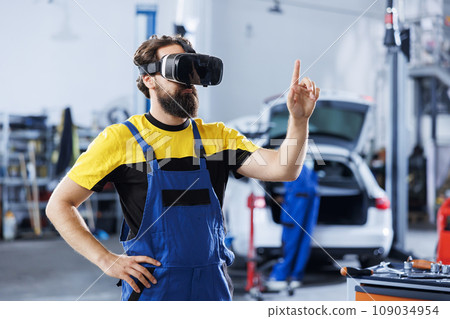 Focused technician in car service uses virtual reality to visualize automobile components in order to repair them. Garage expert wearing high tech vr headset while fixing vehicle issues 109034954