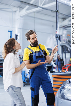 Expert in repair shop using AR technology to show customer car maintenance parameters. Garage worker using futuristic vr headset to inform client of what problems her vehicle is facing 109034974