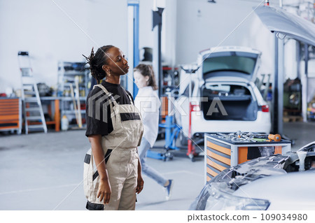 Knowledgeable repair shop employee uses augmented reality to visualize car mechanical parts in order to mend them. Technician using AR technology while working on defective vehicle fuel tank Knowledgeable repair shop employee uses augmented reality to visualize car mechanical parts in order to mend them. Technician using AR technology while working on defective vehicle fuel tank 109034980