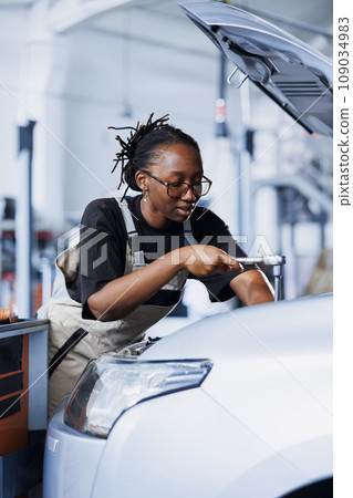 Repair shop technician expertly examines car motor using advanced mechanical tools, ensuring errorless automotive performance. Proactive worker in garage workplace conducts routine vehicle checkup 109034983