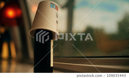 Putting a paper cup on the top of the bottle of red wine while traveling by train in France Putting a paper cup on the top of the bottle of red wine while traveling by train in France 109035443