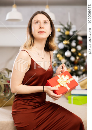 Concentrated woman wants to open a Christmas present Concentrated woman wants to open a Christmas present 109036678