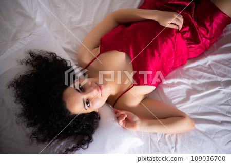 Attractive young girl in red lingerie posing on bed 109036700