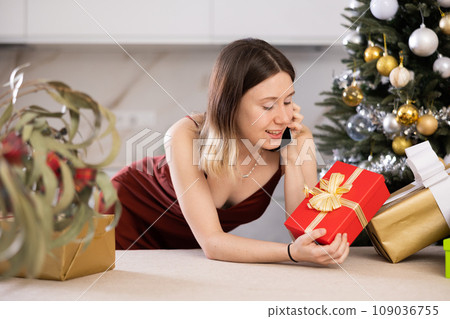 Attractive woman is preparing presents and discussing it with someone on a mobile phone 109036755