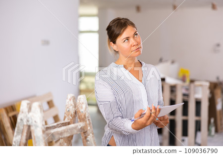 Young woman with papers working on renovation her house Young woman with papers working on renovation her house 109036790