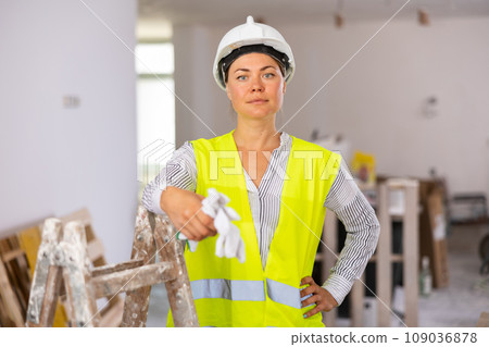 Female architect in yellow vest and hard hat posing at construction site 109036878