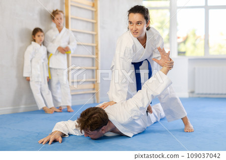 Concentrated woman practicing armlock in sparring with husband at karate training 109037042
