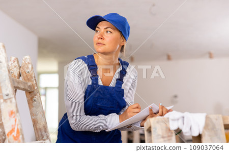 Young woman builder checking project documentation 109037064