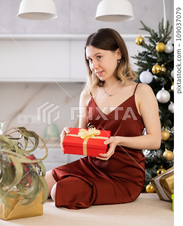 Cheerful woman poses against the background of a Christmas tree Cheerful woman poses against the background of a Christmas tree 109037079