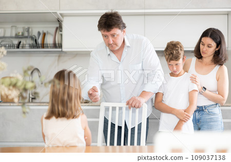 At home in kitchen, parents scold their daughter for careless act 109037138