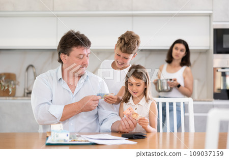 Happy father giving money to children in the kitchen 109037159