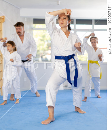 Woman practicing kata routine during family training at karate class Woman practicing kata routine during family training at karate class 109037174