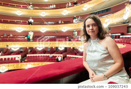 Woman after watching performance poses in auditorium balcony of opera theater Woman after watching performance poses in auditorium balcony of opera theater 109037243