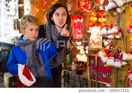 Tween boy with mother looking for Christmas decorations on street market 109037318