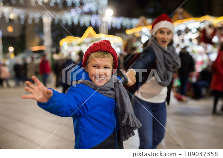 Preteen boy pulling mom hand at outdoor Christmas market Preteen boy pulling mom hand at outdoor Christmas market 109037358